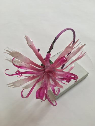 Pink recycled plastic flower on a silk covered metal headband.