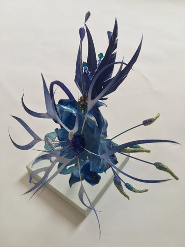 Sapphire blue feather and recycled plastic flowers on a blue silk covered band.