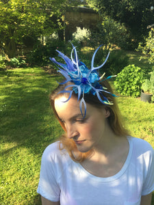 Sapphire blue feather and recycled plastic flowers on a blue silk covered band.