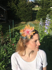 Pink and yellow feather flower with net on a lilac silk headband.