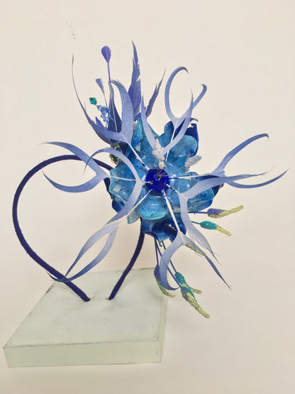 Sapphire blue feather and recycled plastic flowers on a blue silk covered band.